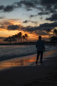 A person walking on a beach at sunset